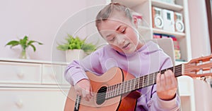 Teen girl is playing ukulele and singing, sitting on the floor.