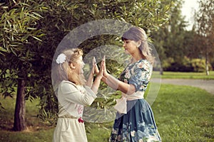 Teen girl plays with mom`s hands in the summer on the nature, re