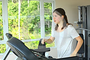 Teen girl with pony tail jogging on treadmill