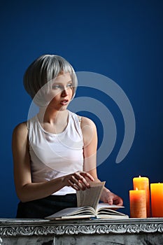 Teen girl posing and leafing through the book. Close up. Blue background