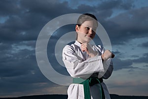 teen girl practicing karate. teen child fighter on sky background. teen kid has green belt