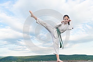 teen girl practicing karate. teen child fighter on sky background. teen kid practicing kick in martial art