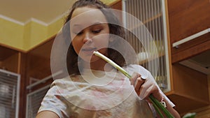 Teen girl preparing salad and singing with Scallions.