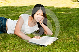 Teen Girl Reading Book on Grass photo