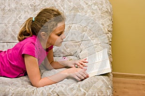 Teen girl reading a book on bed photo