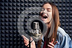 Teen girl in recording studio with mic over acoustic absorber panel background