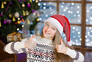 Teen girl in red christmas hat showing thumbs up