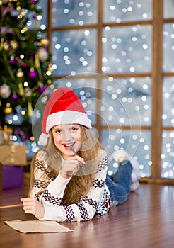 Teen girl in red christmas hat writes letter to Santa Claus