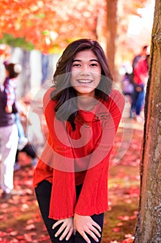 Teen girl in red shirt under red maple tree