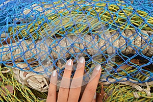 Teen girl`s hand touching colourful fishing nets