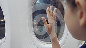 Teen girl says goodbye waving his hand at the window lifestyle of the plane aviation aircraft concept. Young girl looks