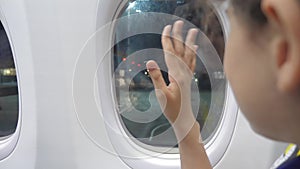 Teen girl says goodbye waving his hand at the window of lifestyle the plane aviation aircraft concept. young girl looks