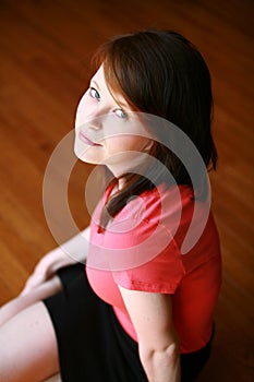 Teen girl seated on wood floor