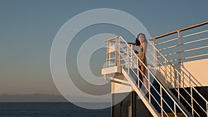 Teen girl in shorts standing on top of blue stairway on ferry boat