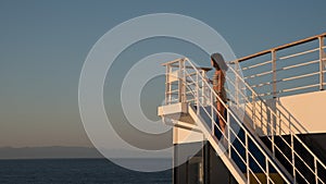 Teen girl in shorts standing on top of blue stairway on ferry boat