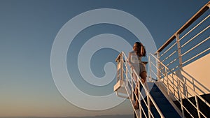 Teen girl in shorts standing on top of blue stairway on ferry boat