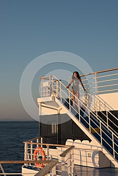 Teen girl in shorts standing on top of blue stairway on ferry boat