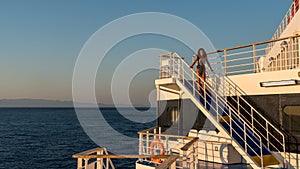Teen girl in shorts standing on top of blue stairway on ferry boat