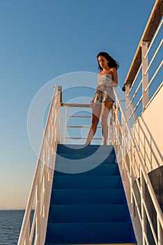 Teen girl in shorts and tube top standing on top stair