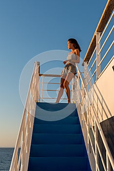 Teen girl in shorts and tube top standing on top stair