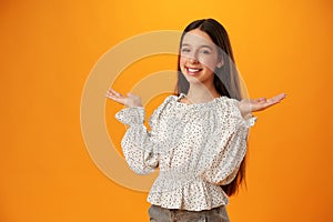 Teen girl shows I don& x27;t know gesture against yellow background