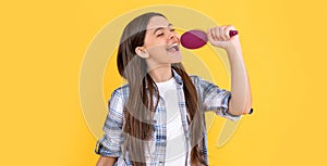 teen girl singing with hairbrush on background. photo of teen girl with hairbrush in hand.