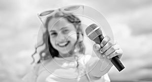 teen girl singing song in microphone on sky background, karaoke music