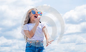 teen girl singing song in microphone on sky background, music party