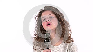 Teen girl sings in retro microphone fiery songs. White background
