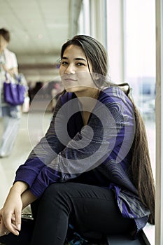 Teen girl sitting at airport waiting for flight