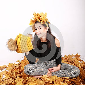 Teen girl sitting on dried leaves with leaves in hair