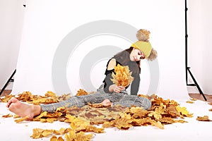 Teen girl sitting on dried leaves in photo atelier