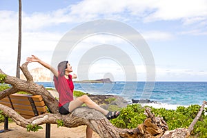 Teen girl sitting on fallen tree by tropical ocean