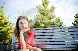 Teen girl sitting outside concerned thinking