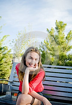 Teen girl sitting smiling outside