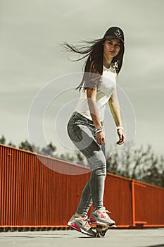 Teen girl skater riding skateboard on street.