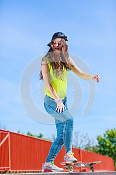 Teen girl skater riding skateboard on street.