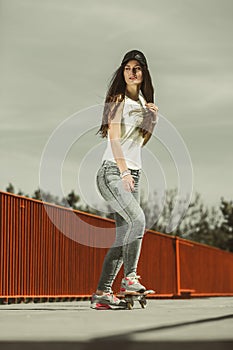 Teen girl skater riding skateboard on street.