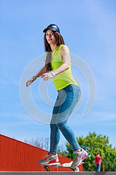 Teen girl skater riding skateboard on street.