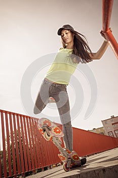 Teen girl skater riding skateboard on street.