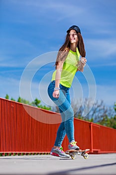 Teen girl skater riding skateboard on street.