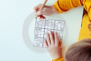 Teen girl solving sudoku at desk at school or at home. View from above