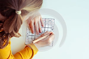 Teen girl solving sudoku at desk at school or at home. View from above