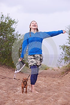 Teen girl standing on the beach with her dog