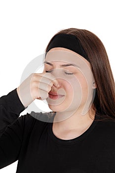 Teen girl standing with eyes and nose closed for stink