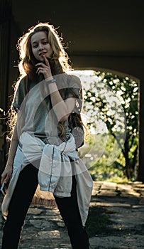 Teen girl stands in the arch at sunset. Silhouette of a girl with long hair