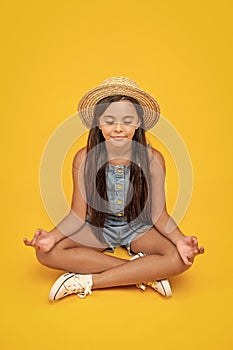 teen girl in straw hat meditating on yellow background