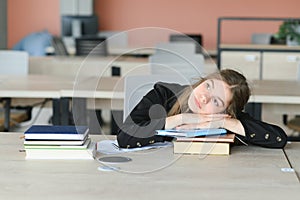 Teen girl studying with textbook writing essay learning in classroom.