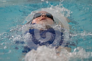 Teen girl swimming in a pool during a competition