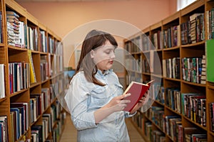 Teen girl taking   book from bookshelves in library, choosing